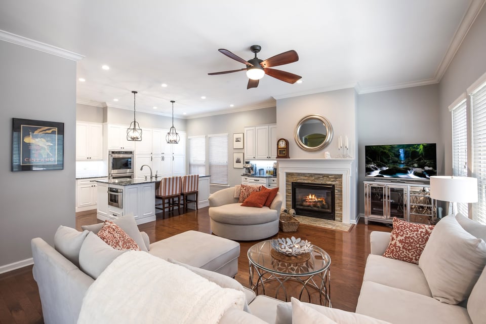 Open concept home renovation in Jacksonville with white kitchen cabinets, hardwood floors, and fireplace