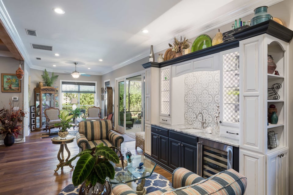Elegant sunroom with striped armchairs and glass coffee table by BeeTree Homes in Jacksonville Beach, FL