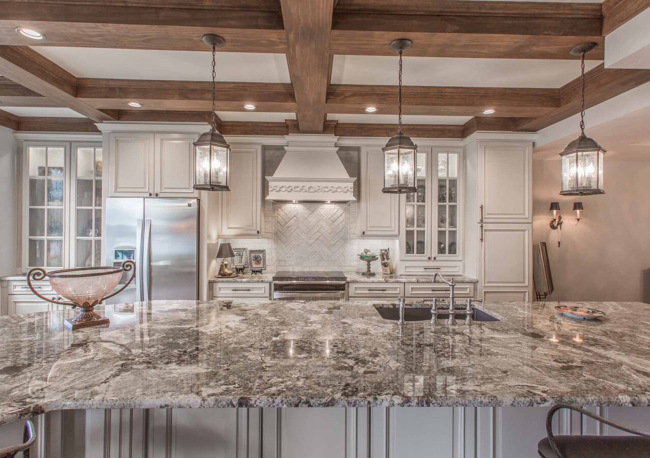 Large island kitchen with pendant lighting and marble countertops in BeeTree Homes custom home