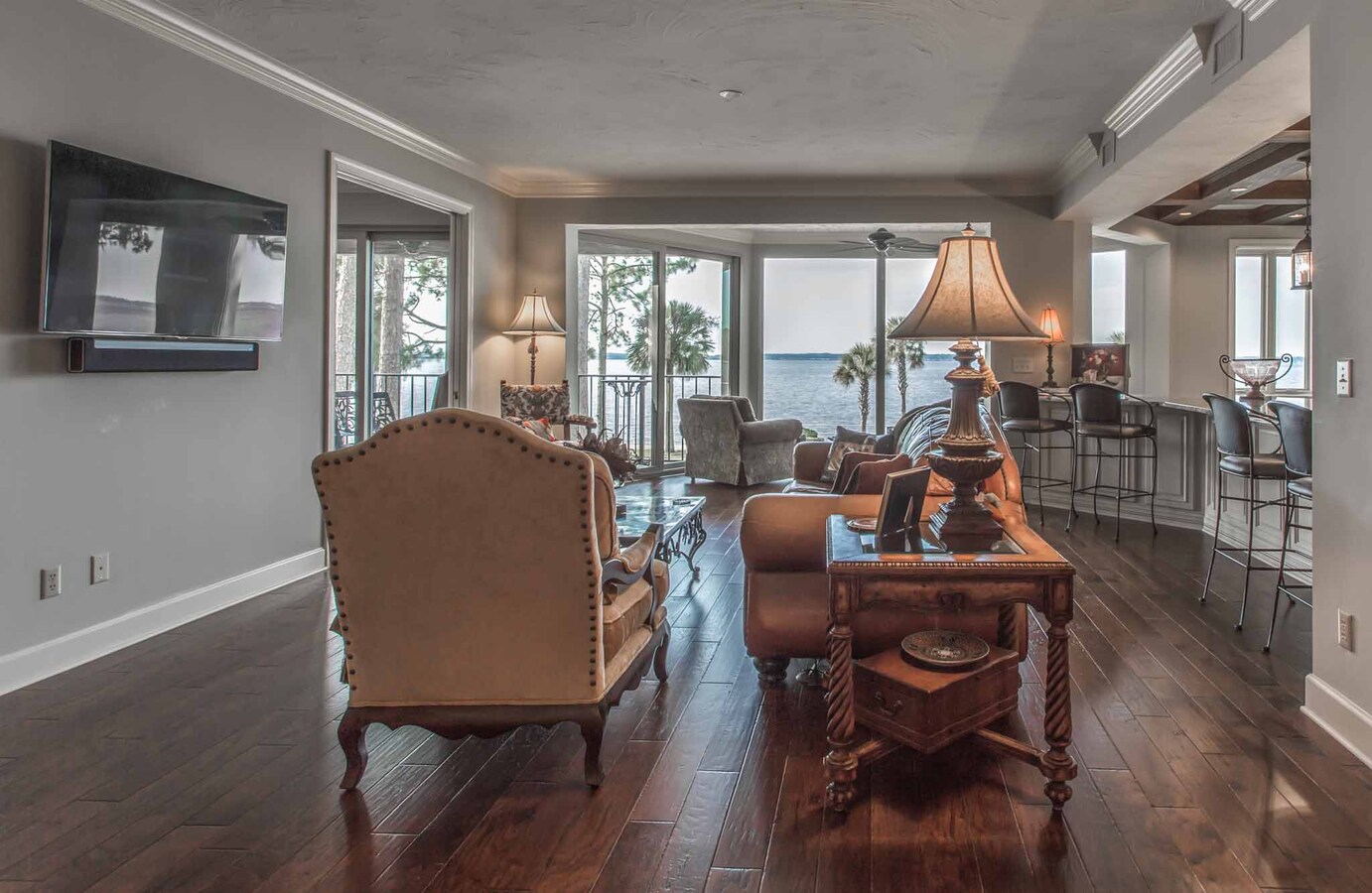 Water-facing living area with warm-toned furniture in custom Jacksonville, FL home by BeeTree Homes