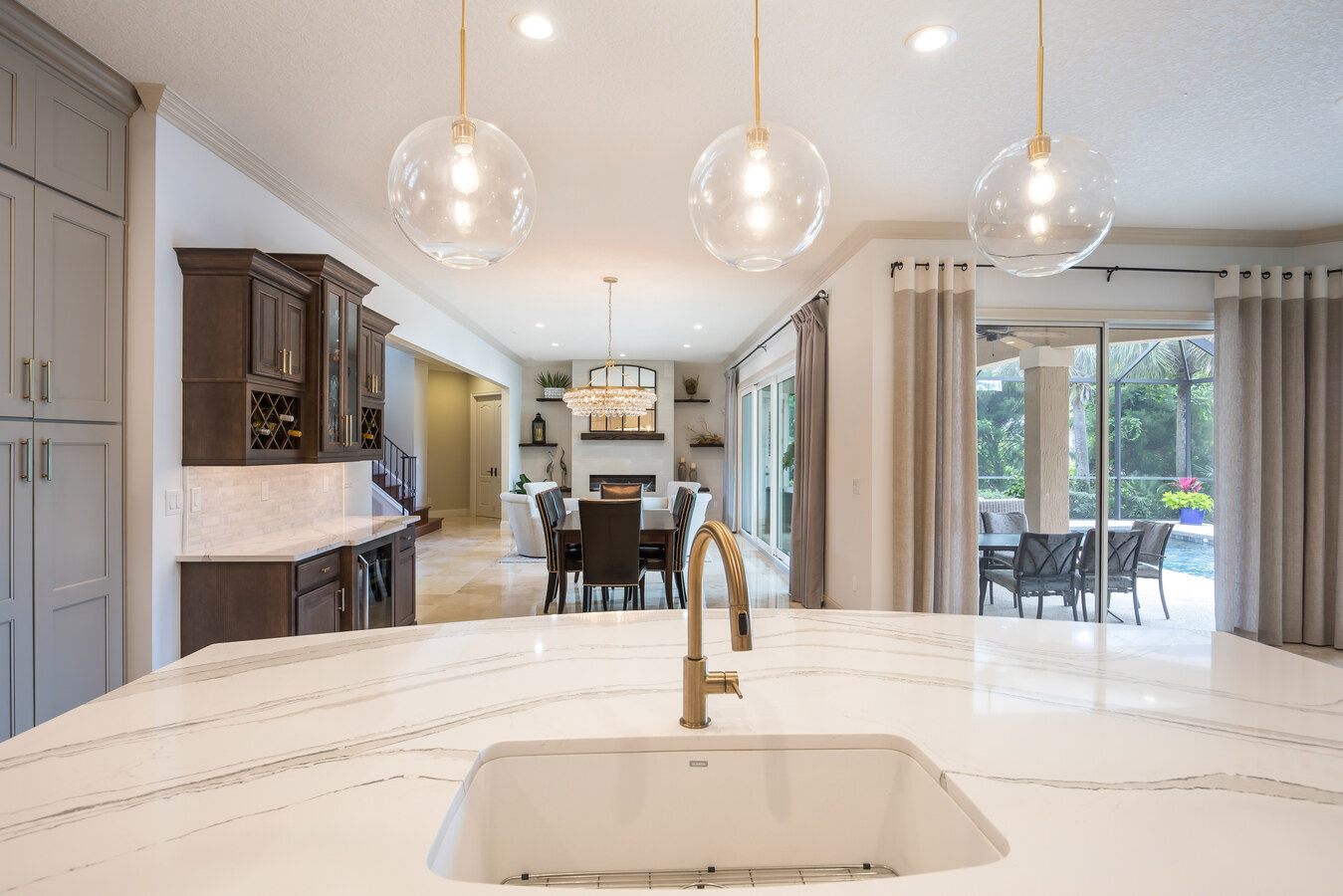 Dining and kitchen view from marble island by BeeTree Homes in Jacksonville, FL with poolside backdrop