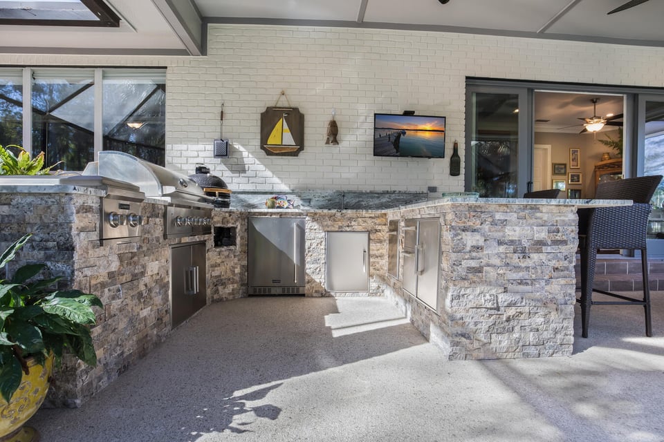 Stone-clad outdoor kitchen with stainless appliances in BeeTree Homes custom build, Ponte Vedra Beach, FL