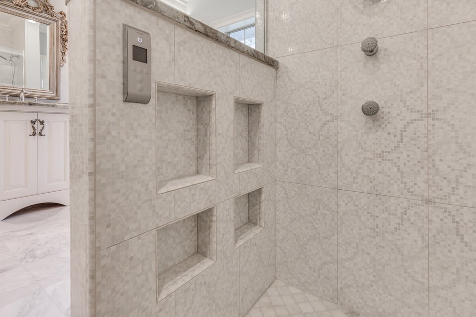 Detail of tiled shower wall with built-in shelves and control panel by BeeTree Homes in Jacksonville