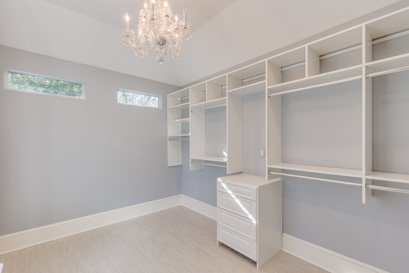 Organized walk-in closet featuring custom shelves and soft gray walls by BeeTree Homes Jacksonville