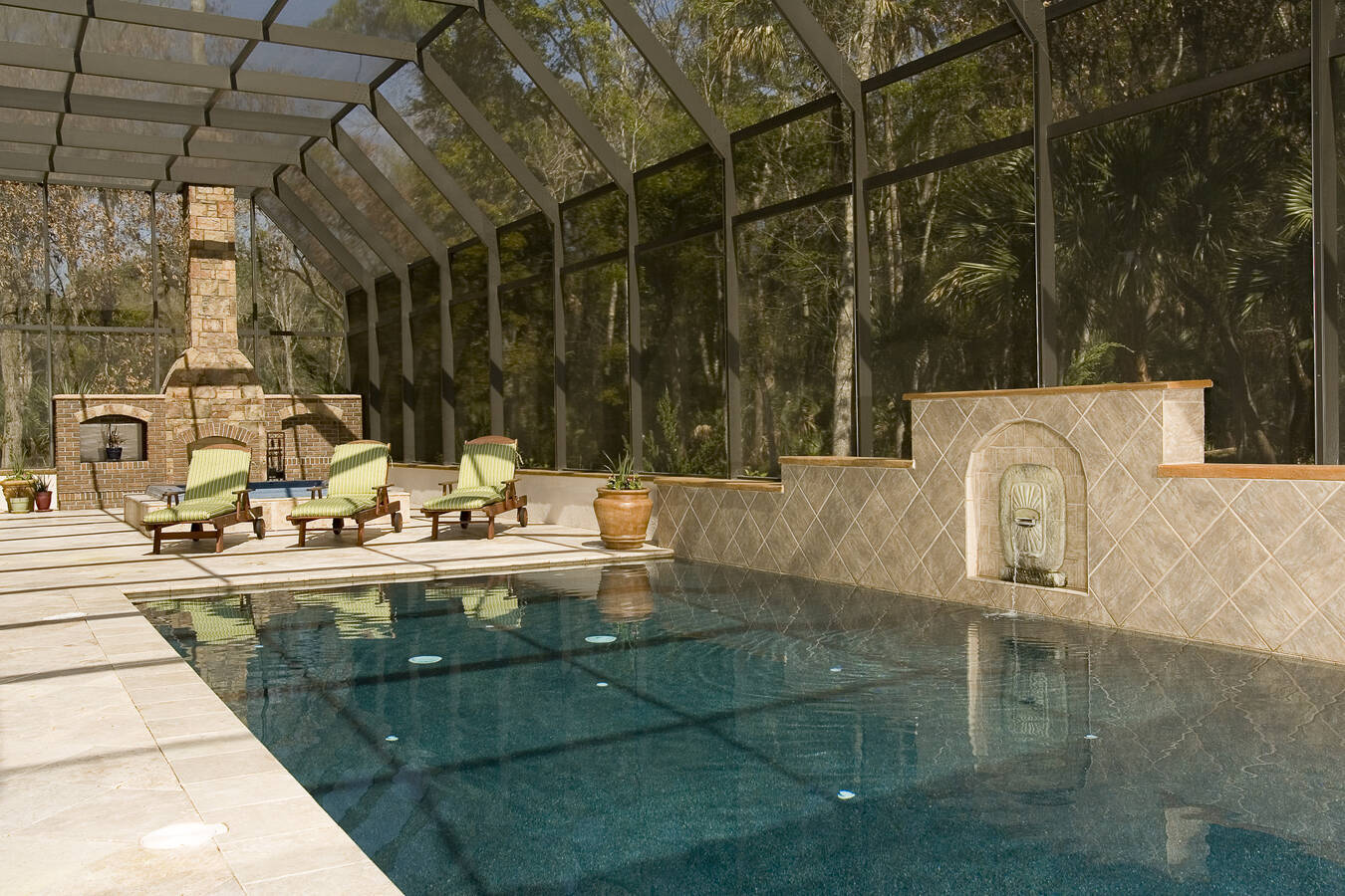 Enclosed pool with lounge seating and tile water feature in Jacksonville custom home by BeeTree Homes