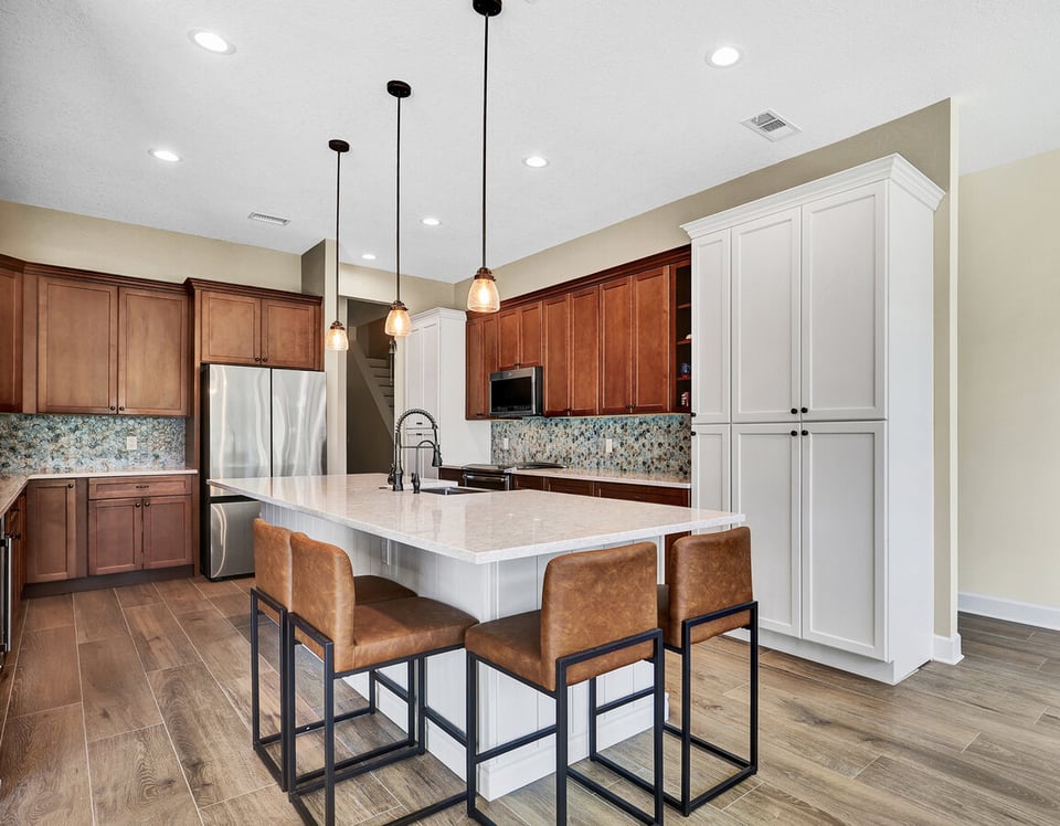 Spacious kitchen remodel featuring wood cabinetry and quartz island by BeeTree Homes in Jacksonville