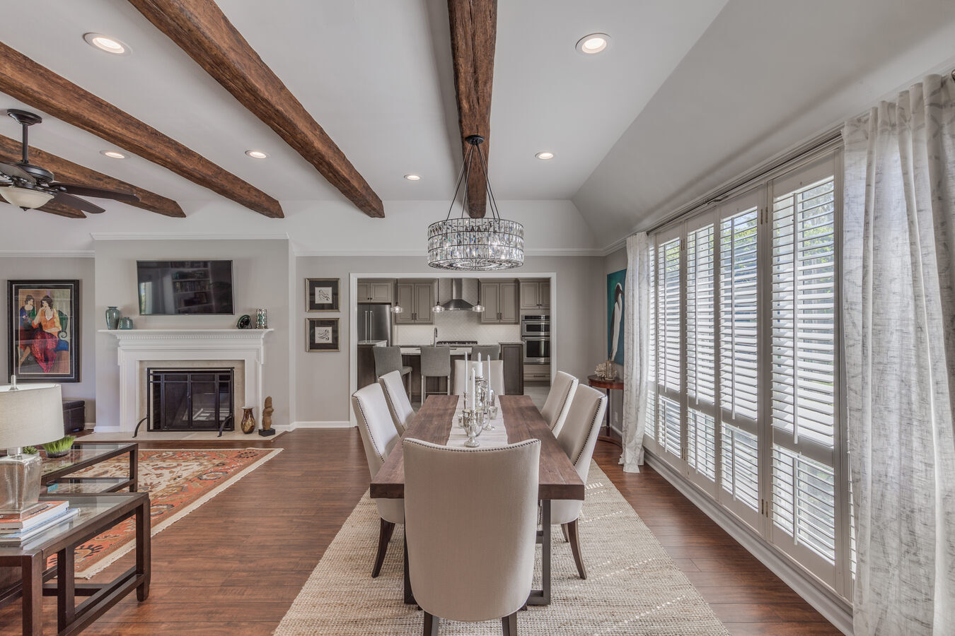 Open-concept living and dining space with wood ceiling beams by BeeTree Homes in Jacksonville, FL