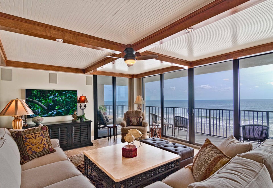Ocean-facing living space with natural lighting and wood-beamed ceiling by BeeTree Homes Jacksonville