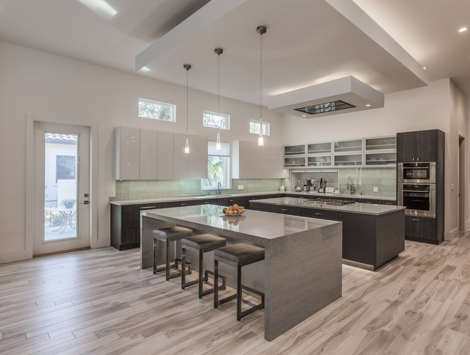 Modern kitchen design featuring high-gloss cabinets and large island seating by BeeTree Homes, Jacksonville