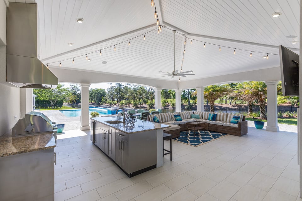 Covered outdoor kitchen and lounge area with pool views in a BeeTree Homes custom build in Jacksonville, FL