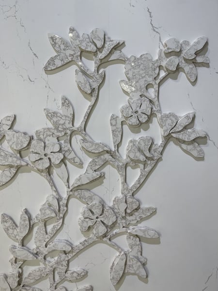 Backlit floral wall art made from layered white and gray veined stone.