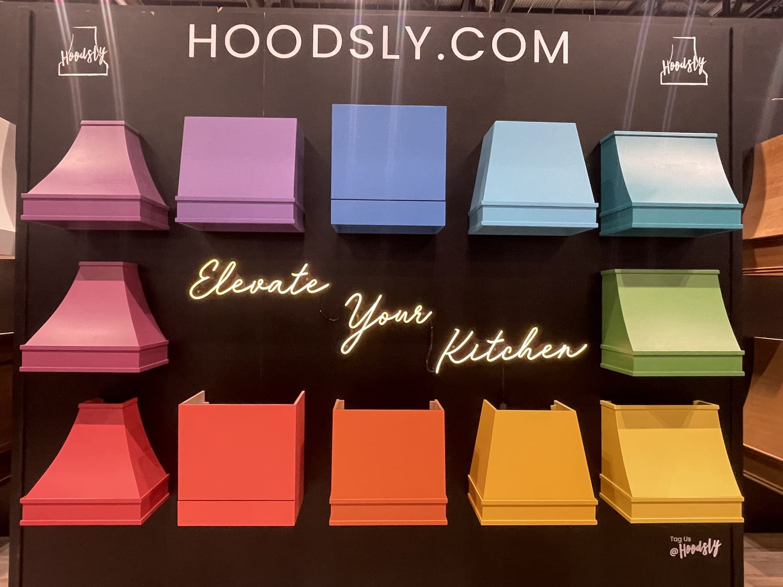 Colorful custom range hood display in pink, purple, blue, green, orange, and yellow finishes.