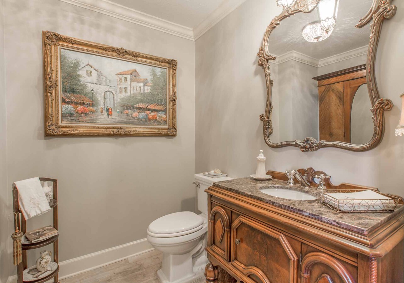 Sophisticated powder room with detailed mirror and wood vanity in custom BeeTree Homes project