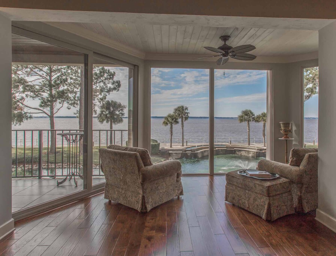Waterfront sitting area with large windows and plush chairs in BeeTree Homes custom home, Jacksonville