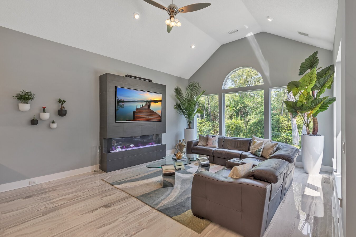 Open and airy great room with sectional sofa and large windows in a custom home by BeeTree