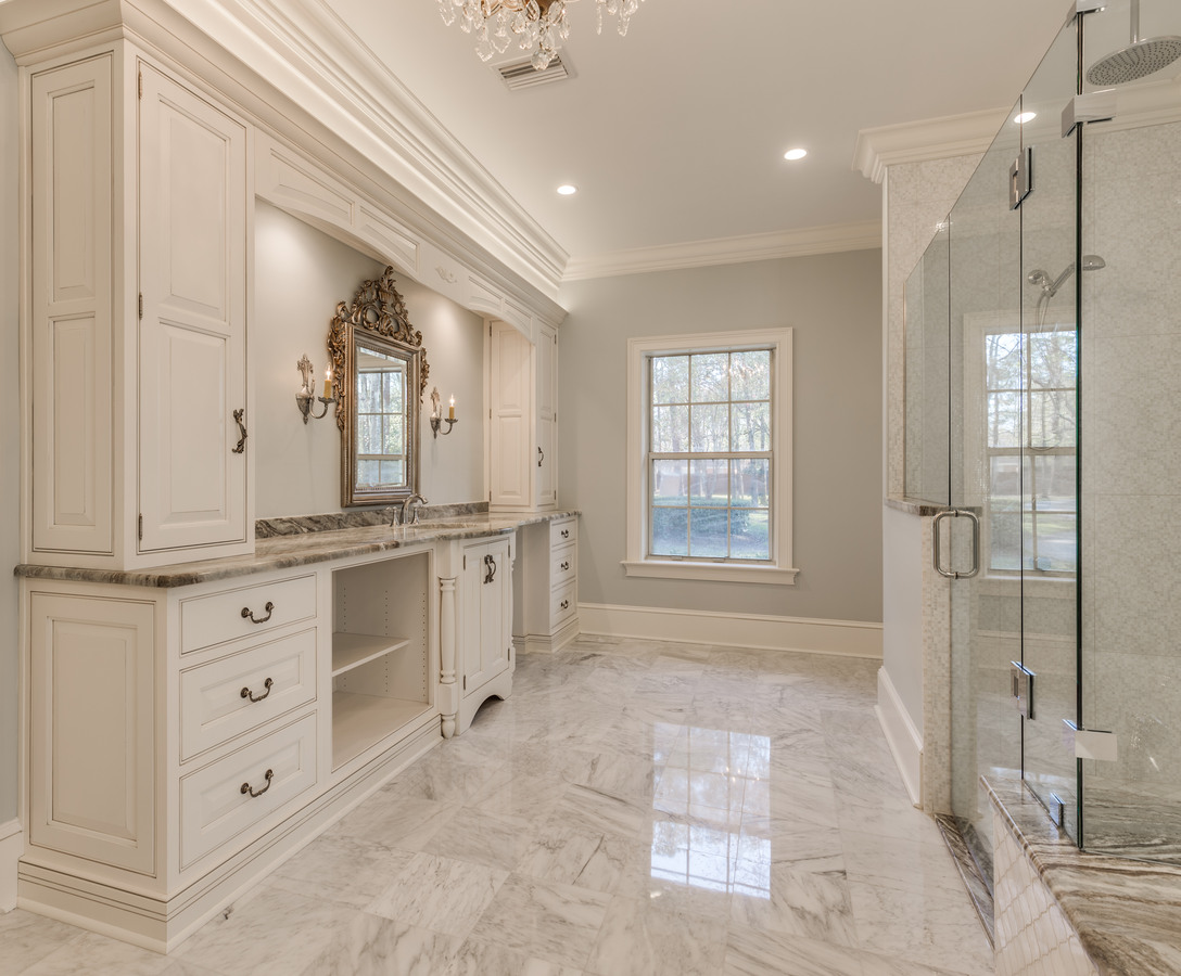 Ornate bathroom with marble finishes and glass shower enclosure by BeeTree Homes in Jacksonville, FL