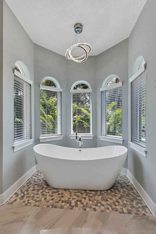 Freestanding bathtub on mosaic tile in bright bathroom nook by BeeTree Homes in Jacksonville FL