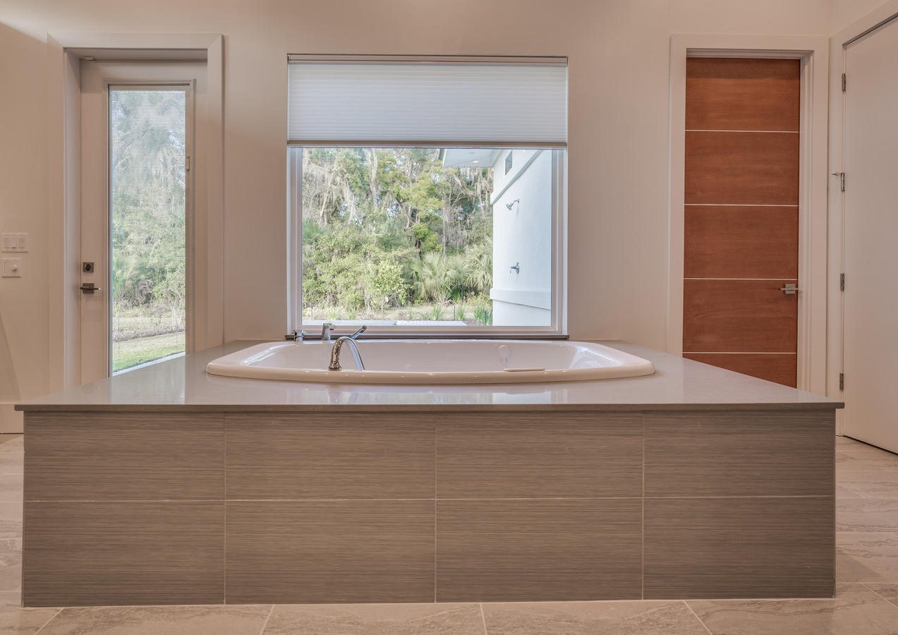 Spa-like soaking tub with natural light in custom Jacksonville, FL bathroom by BeeTree Homes