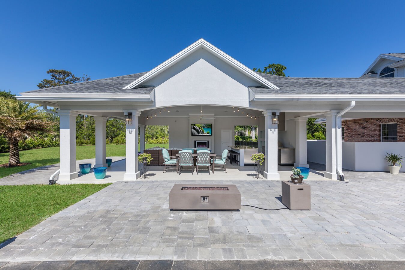 Rear view of a custom outdoor living space with dining and lounge area by BeeTree Homes