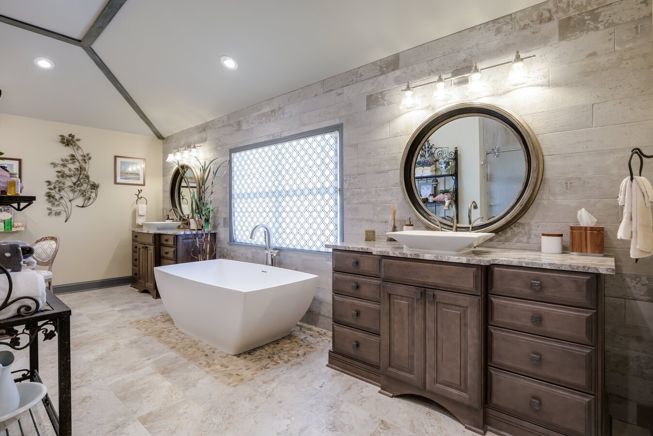 Elegant custom bathroom with stone tile walls and wood cabinetry in Jacksonville, FL by BeeTree Homes